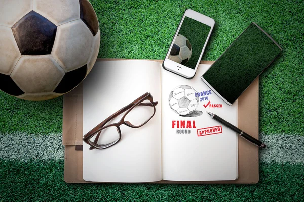 Soccer ball, sketch book, glasses, smartphone on green artificia — Zdjęcie stockowe