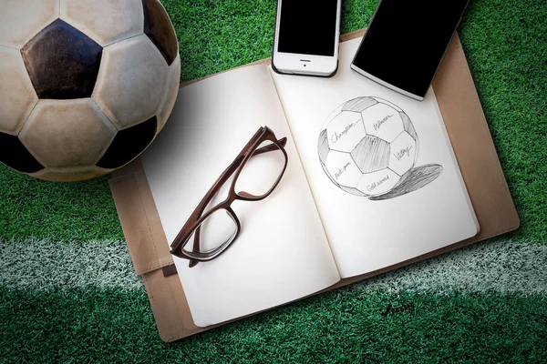 Soccer ball, sketch book, glasses, smartphone on green artificia — Stockfoto