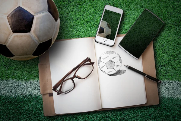 Soccer ball, sketch book, glasses, smartphone on green artificia — Stockfoto