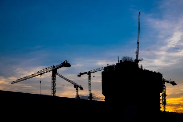 Industrial construction cranes and building silhouettes over sun — Stock Photo, Image