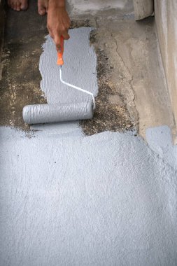 Çatıdaki su yalıtımı için tekerlekli fırçası olan bir işçi. Bangkok, Tayland 'da Ev Yenileme. 5 Ekim 2019