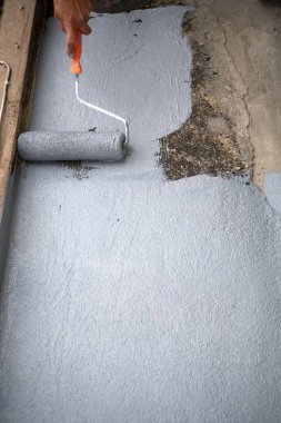 Çatıdaki su yalıtımı için tekerlekli fırçası olan bir işçi. Bangkok, Tayland 'da Ev Yenileme. 5 Ekim 2019