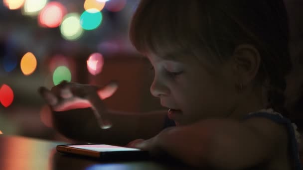 Kleines Mädchen betrachtet Fotos auf dem Smartphone — Stockvideo