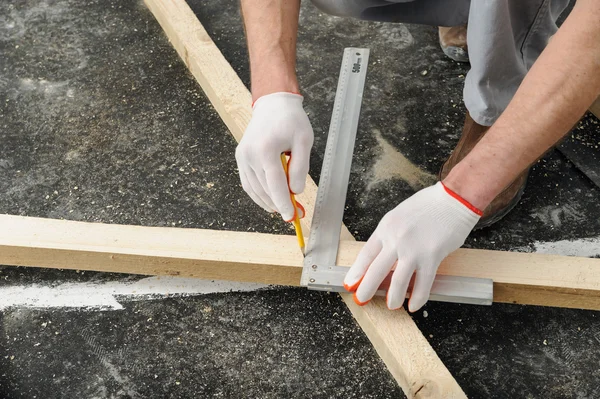 El trabajador mide una viga de madera . — Foto de Stock