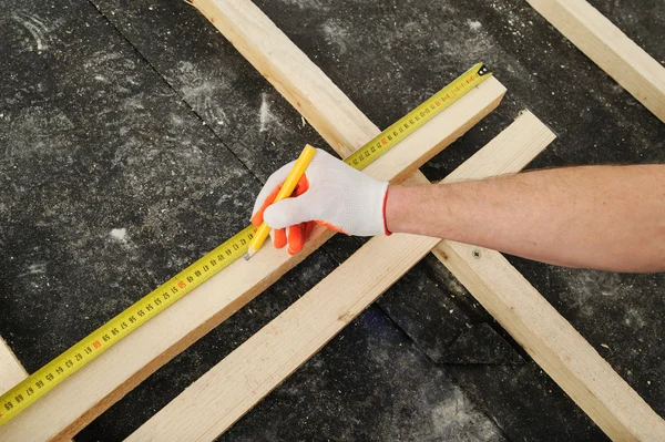 Il lavoratore misura una trave di legno . — Foto Stock
