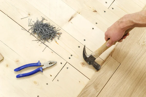 铺设硬木实木复合地板 工人修复板一个接一个 — 图库照片