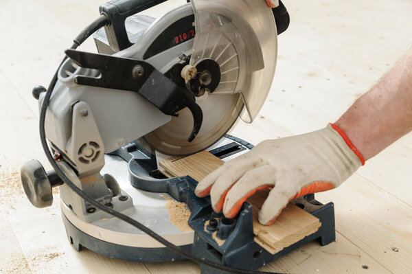 Worker cuts wooden floorboards.