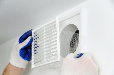 Worker installs ventilation grille on the wall. clipart