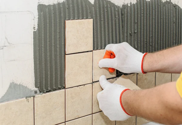 Trabajador poniendo azulejos en la pared en la cocina. —  Fotos de Stock