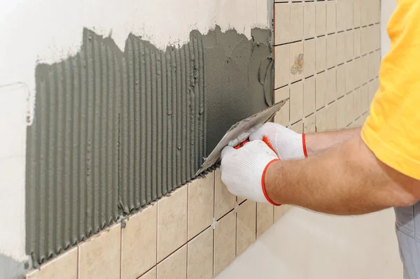Worker instiling tiles on the wall in the kitchen. Stock Picture