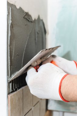 İşçi mutfaktaki duvara fayanslar koyuyor..