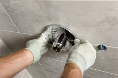 İşçinin elleri dahili bir musluk takıyor..