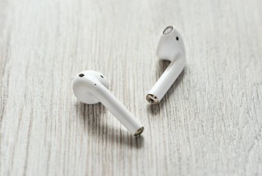 Tahta arka planda dokunmatik kulaklıklı beyaz kablosuz kulaklık..