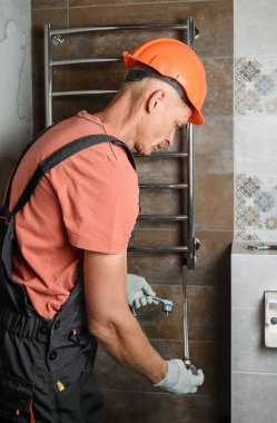 İşçi banyodaki havlu ısıtıcısına ısıtıcı yerleştiriyor..