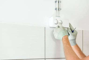 Bir işçi havalandırma sisteminin nem sensörünü bağlıyor..