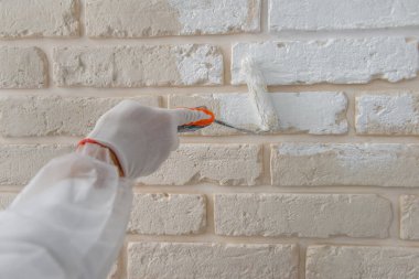 İşçi, rpaint oller ile tuğla duvar boyuyor..