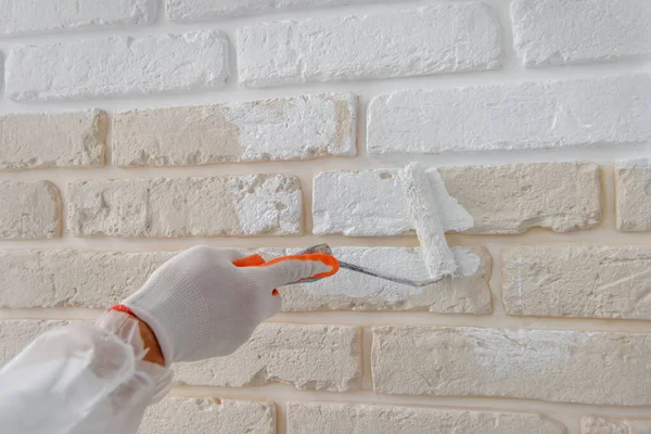 İşçi, rpaint oller ile tuğla duvar boyuyor..