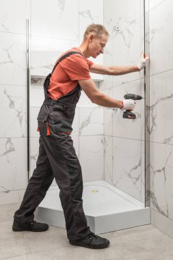 İşçi, duş kabininin metal bir profilini tornavidayla yüklüyor..