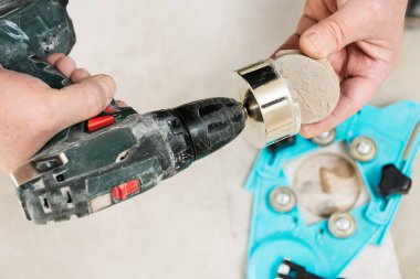 Bir tiler seramik fayansta delikler açmak için elmas bir taç kullanıyor..