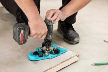 Bir tiler seramik fayansta delik açmak için vakum kabıyla kalibre kullanır.