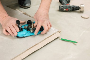 Bir tiler seramik fayansta delik açmak için vakum kabıyla kalibre kullanır.