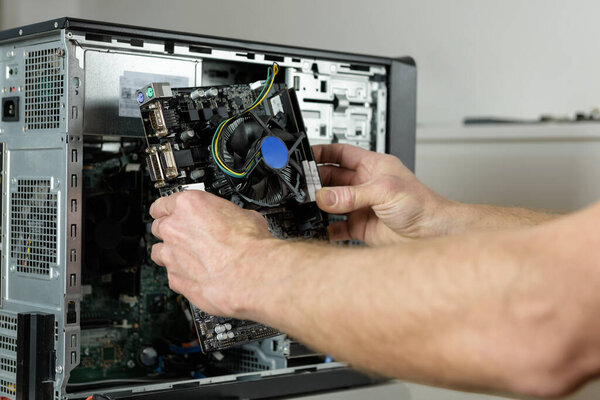 A technician is installing the motherboard in the desktop case.