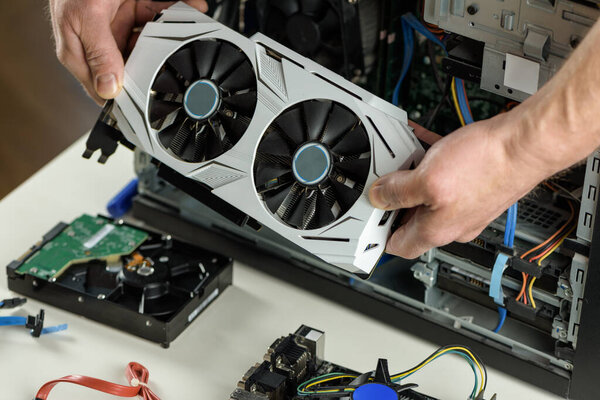 Human hands are inserting a video card into a computer.