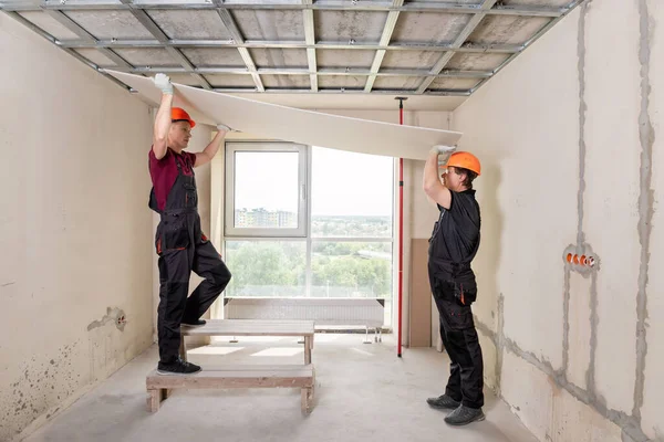 Installation Von Trockenbau Arbeiter Heben Trockenbau Ihn Der Decke Befestigen lizenzfreie Stockbilder