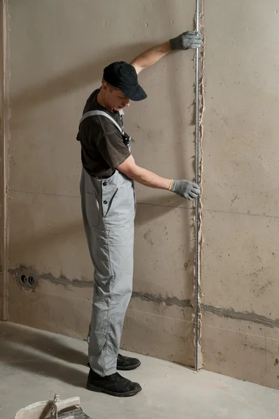 Man fixes a guide to align the walls with stucco — Stock Photo, Image