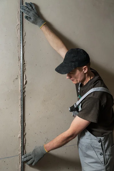 Woker fixes a guide to align the walls with stucco — Stock Photo, Image