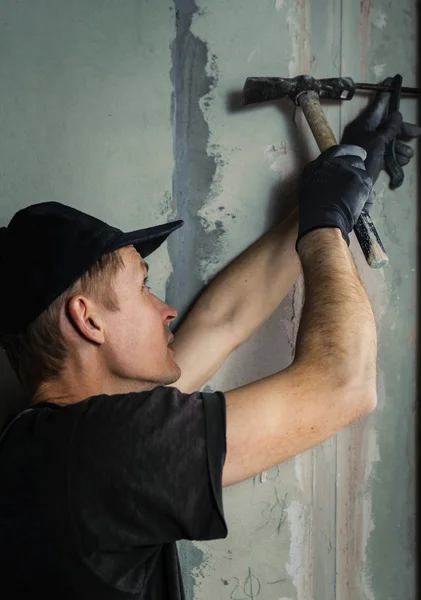 Woker martella un chiodo con un piede in un muro — Foto Stock