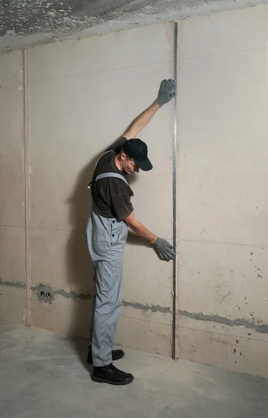 Woker fixes a guide to align the walls with stucco — Stock Photo, Image