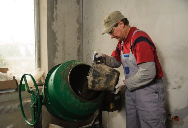 Adam işçi çözüm için mikser malzeme doldurur