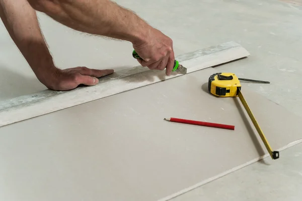 Mann schneidet ein Stück Trockenbau ab — Stockfoto