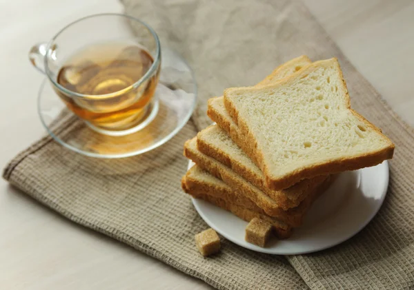 Toast sur une soucoupe, des cubes de sucre et une tasse de thé — Photo
