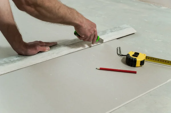Homem corta um pedaço de drywall — Fotografia de Stock