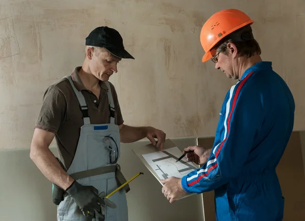 Pracovníka a foreman diskutovat schéma sádrokartonového podhledu — Stock fotografie