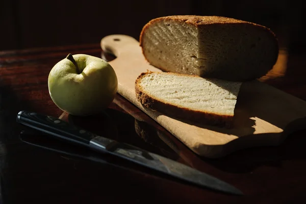 Homemade bread, an apple and a knife on the table — Stock fotografie