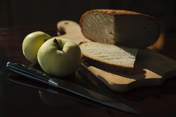 Домашний хлеб, два яблока и нож на столе — стоковое фото