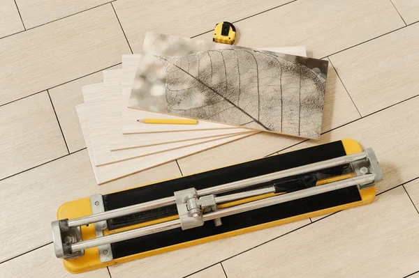 Керамическая плитка, ручной резак, измерительная лента и карандаш — стоковое фото