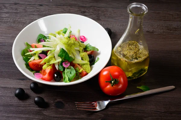 Ensalada en plato, al lado de tomate y tenedor — Foto de Stock