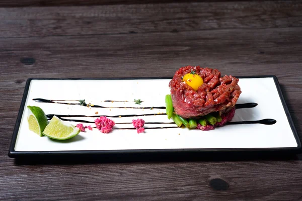 Tartar of beef served with lime on white dish — Stock Photo, Image