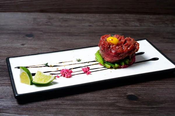 Tartar of beef served with lime on white dish — Stock Photo, Image