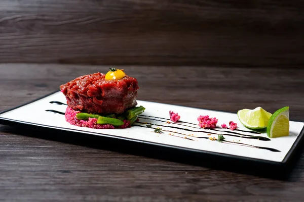 Tartar of beef served with lime on white dish — Stock Photo, Image