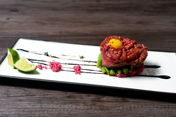 Tartar of beef served with lime on white dish — Stock Photo, Image