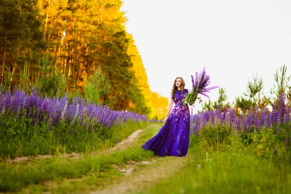 Meisje in een gebied van paarse wilde bloemen — Stockfoto