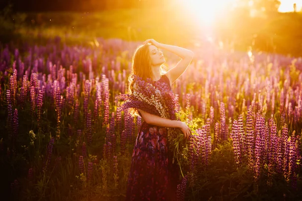 Tjejen i lila blommor, solnedgång på Sunny day området — Stockfoto