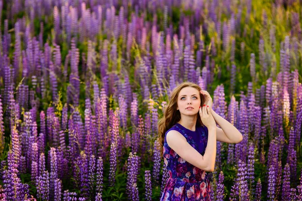 Menina com flores tremoços em um campo ao pôr do sol — Fotografia de Stock