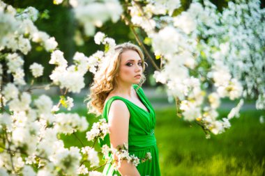 Şu yeni gelişen bir elma ağacı duran güzel genç sarışın kadın