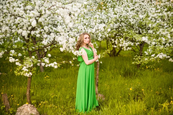 Bella giovane donna bionda in piedi accanto a un albero di mele in fiore — Foto Stock